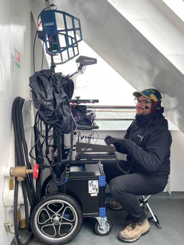 Reid Miller at a sound cart on a ferry boat under stairs with antennas folded down to fit in the space